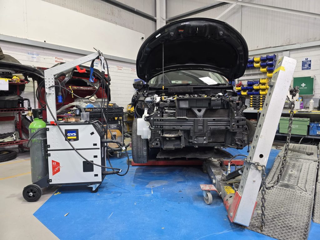 In-progress repair on car in workshop showing equipment.